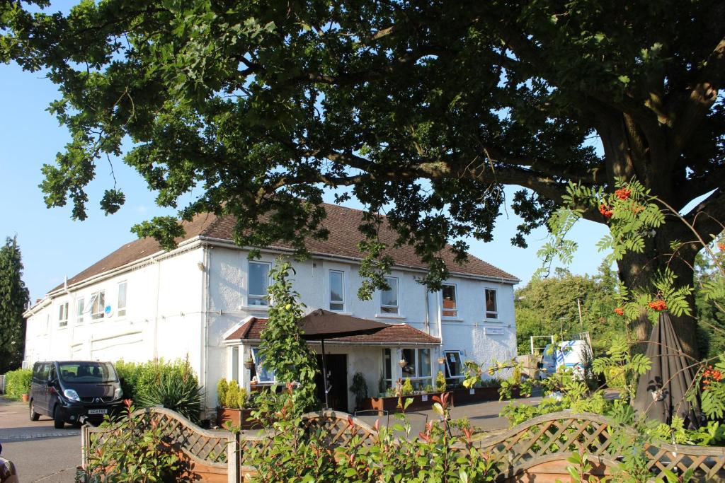 ein weißes Haus mit einem Baum davor in der Unterkunft The Gatwick White House Hotel in Horley