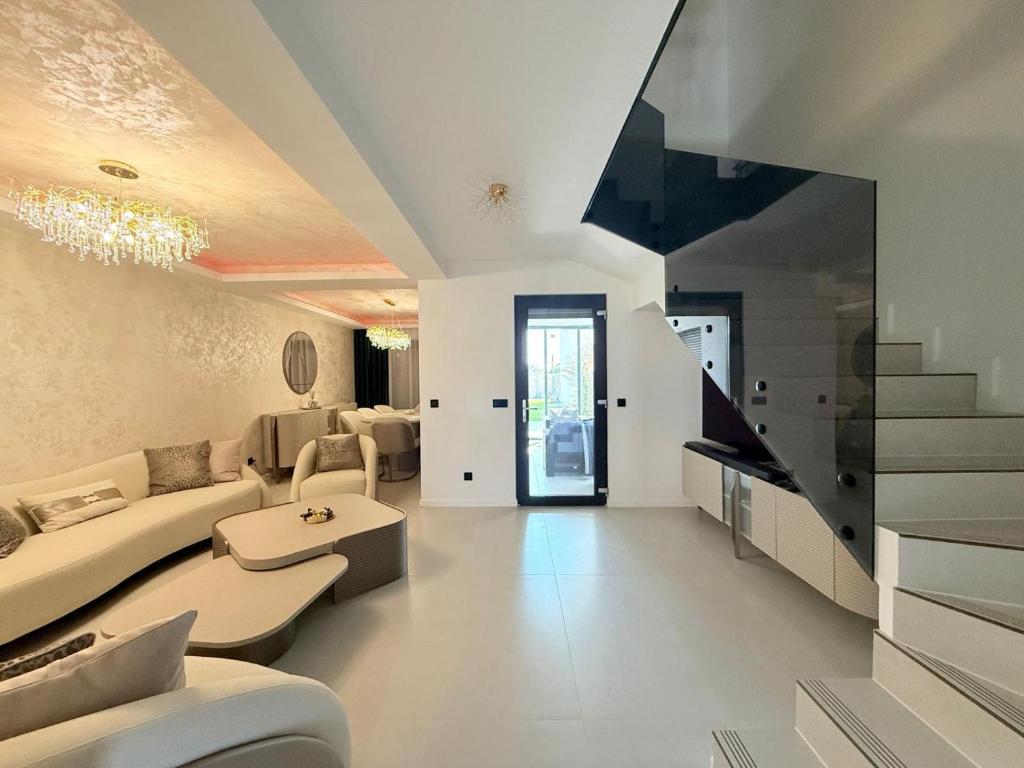 ein Wohnzimmer mit weißen Möbeln und einer Treppe in der Unterkunft Royal Residence in Moşniţa Nouă