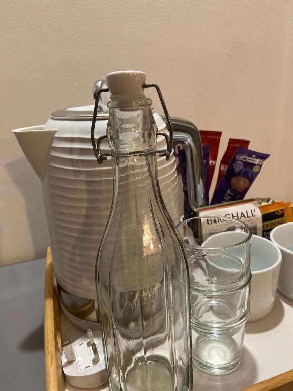 a glass bottle and a glass cup on a table at Rhubarb Barn bedroom only in Diss
