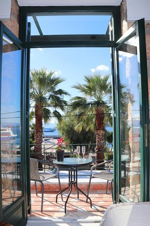 an open patio door with a table and palm trees at Stone House Edipsos in Loutra Edipsou
