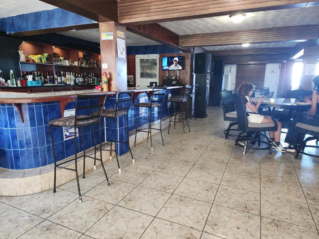 a woman sitting at a bar in a restaurant at Hotel Colombus in Aguada