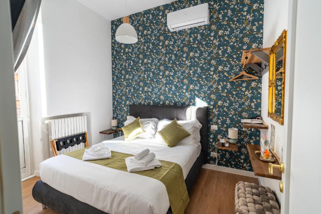 1 dormitorio con 2 camas y pared con papel pintado con motivos florales en NOI Luxury rooms Colosseum, en Roma