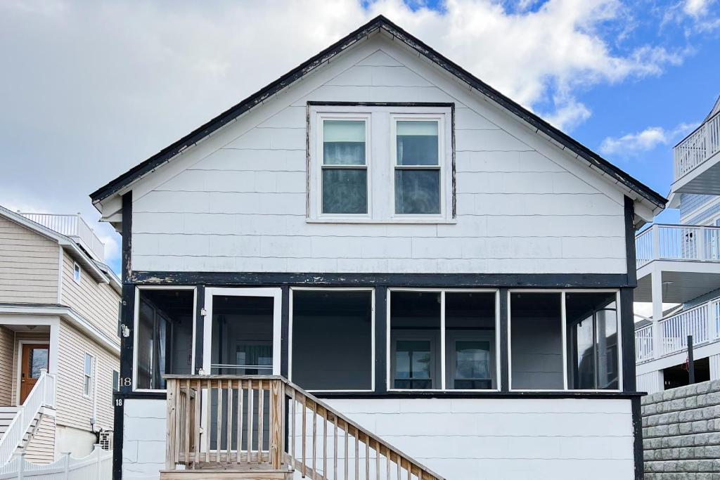 a white house with large windows and a staircase at Flip Flops & Sand Beach house in Wells