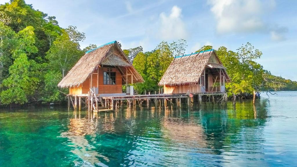 a couple of houses on a dock in the water at OMBAR Homestay in Minyaifuin