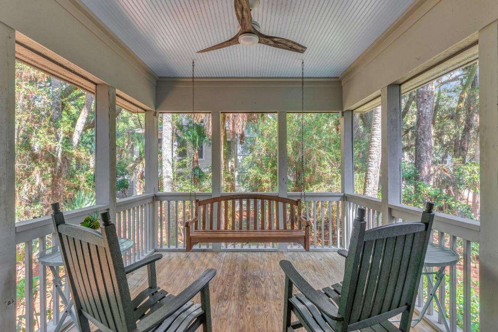 a screened porch with rocking chairs and a bench at SI2638: 2638 Seabrook Island Road in Seabrook Island