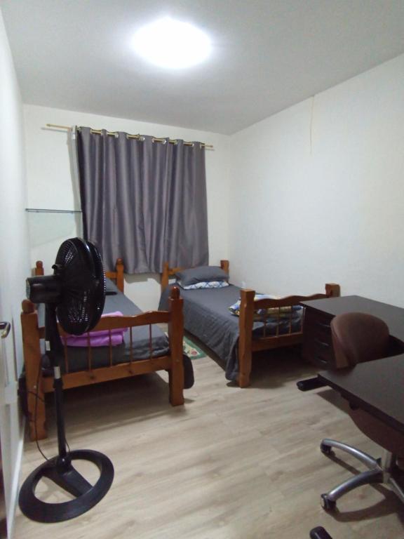 a bedroom with two bunk beds and a desk and a table at Casa aconchegante e familiar no bairro Vila Nova in Joinville