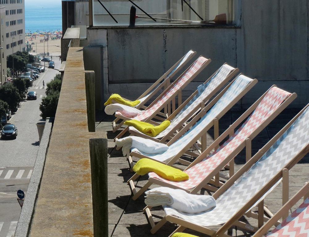 een rij ligstoelen met gele kussens op een gebouw bij Porto 3 Bedroom Beach Apartment in Matosinhos