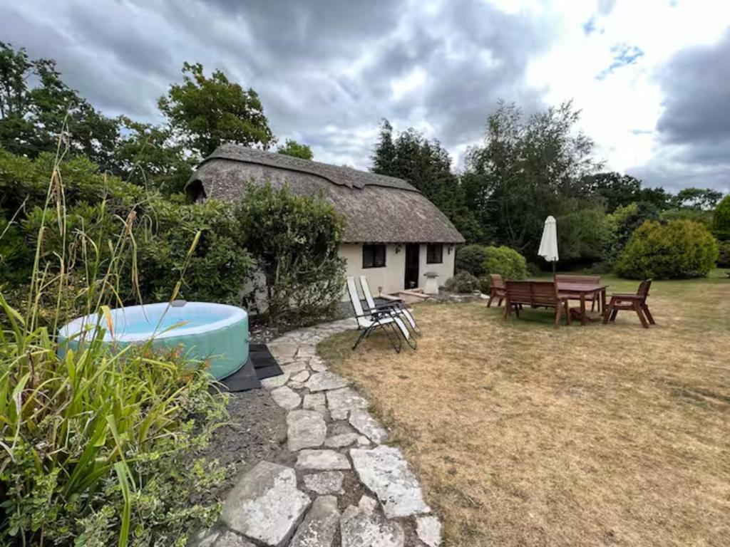 a cottage with a table and a tub in a yard at Stag Cottage New Forest Romantic Hideaway in Burley