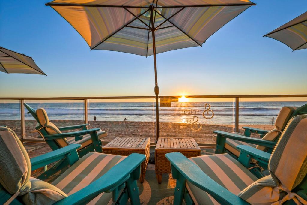 a group of chairs and an umbrella on the beach at Seashore On The Sand in Carlsbad