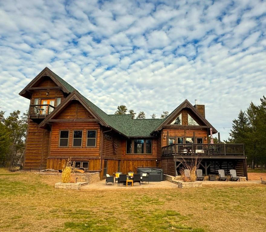 una grande casa di tronchi con una terrazza su un campo di Lake Tower Lodge a New Rome