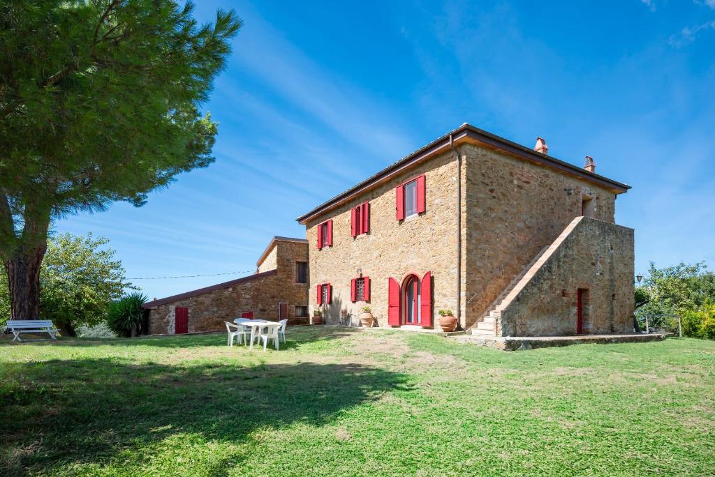 un vecchio edificio in mattoni con finestre rosse e un tavolo di IL MELOGRANO a Scarlino
