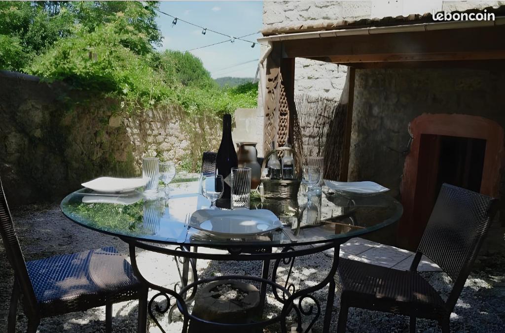 a glass table with a bottle of wine and chairs at Appartement de charme en Ardèche in Aubenas