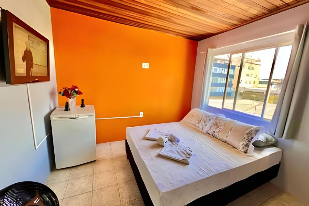a bedroom with orange walls and a bed with a window at #MaReSiaSdaPaz próximo ao centro de Matinhos in Matinhos