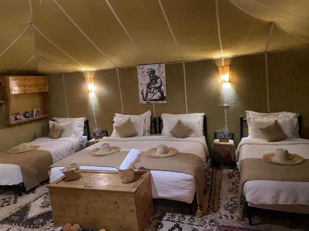a bedroom with three beds in a tent at DesertGlow camp in Merzouga