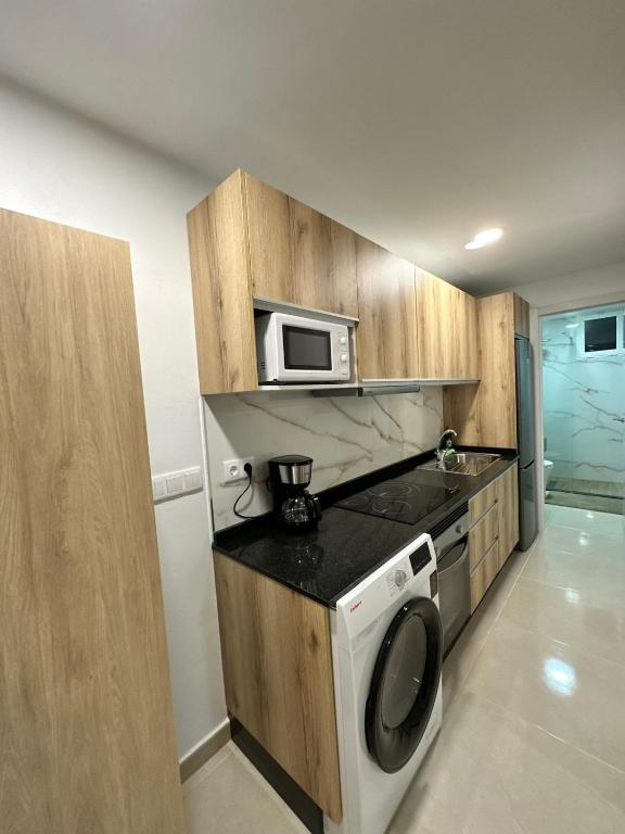 a kitchen with a microwave and a washing machine at Apartamento Studio Anau k&L- Playa del inglés - Yumbo in Playa del Ingles