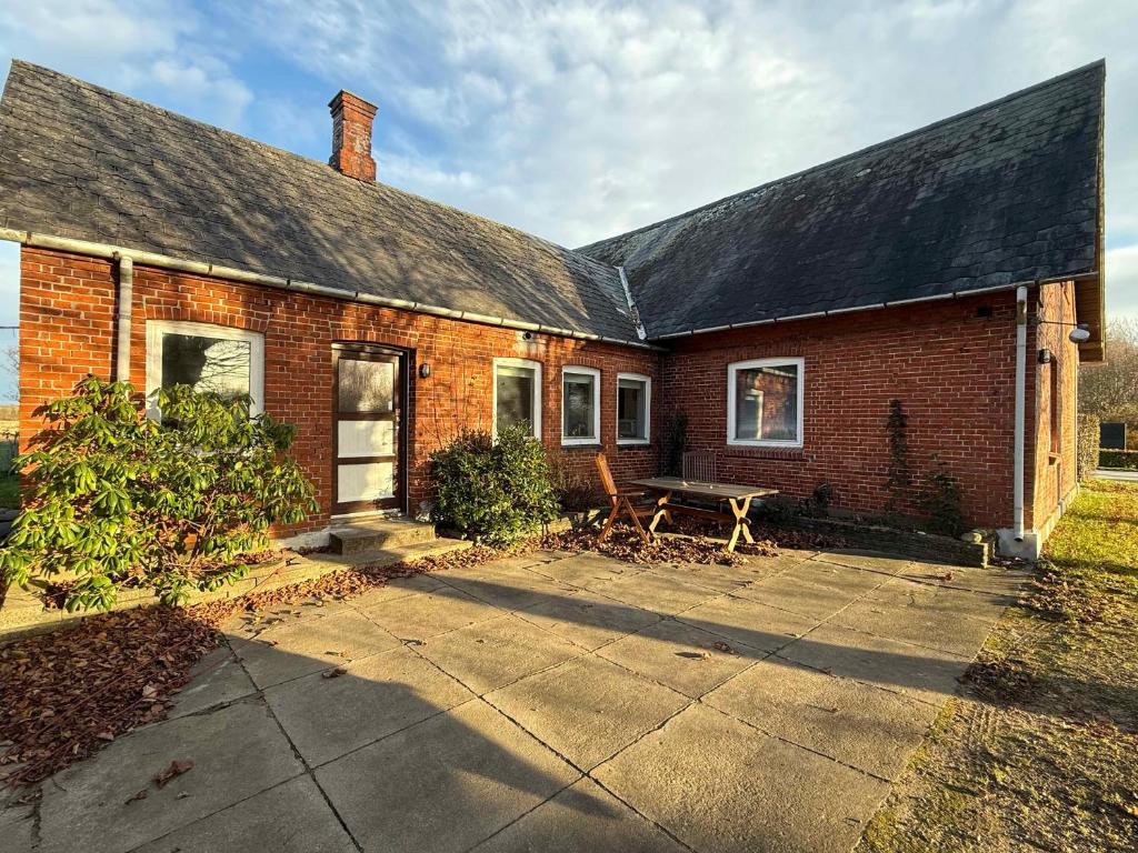 a brick house with a picnic table in front of it at The Coziest Farm Holiday In The Countryside in Tommerup
