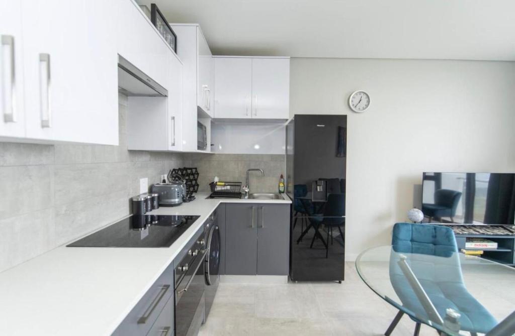 a kitchen with white cabinets and a table and chairs at Beachfront Getaway in Gqeberha