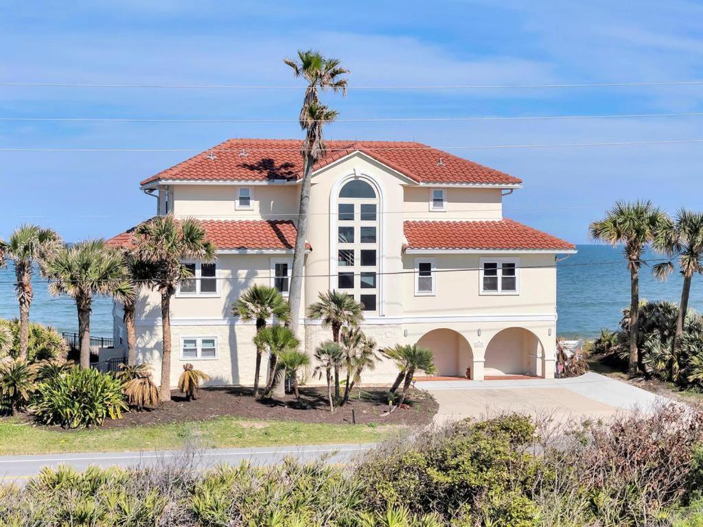 een groot wit huis met palmbomen voor de oceaan bij Sea Haven - Oceanfront home w pvt beach & deck in Ponte Vedra Beach