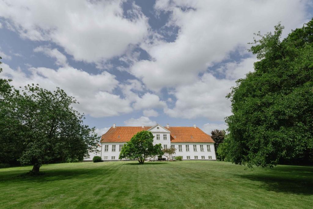 a large white building with an orange roof on a green field at Hindemae Estate For Holidays And Events in Ullerslev