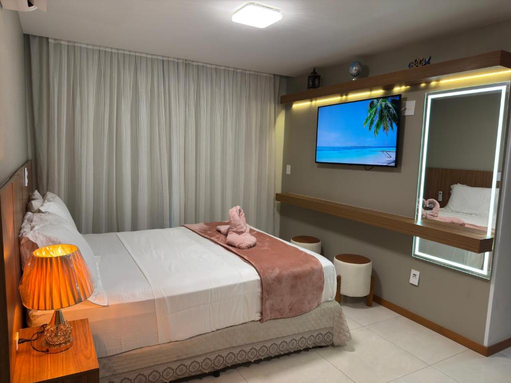Un dormitorio con una cama y un televisor en la pared. en Magnífico APARTAMENTO de Charme - 3 quartos AR CONDICIONADOS SPLIT - Beira Mar, 2 banheiros, 2 Vagas Garagem, 4 Varandas, 2 Elevadores, Redes para Descanso, Wi-Fi, Air Fryer, Disney Plus, HBO Max, Guarda Sol, Cadeiras de Praia e Caixa Térmica, en Guarapari