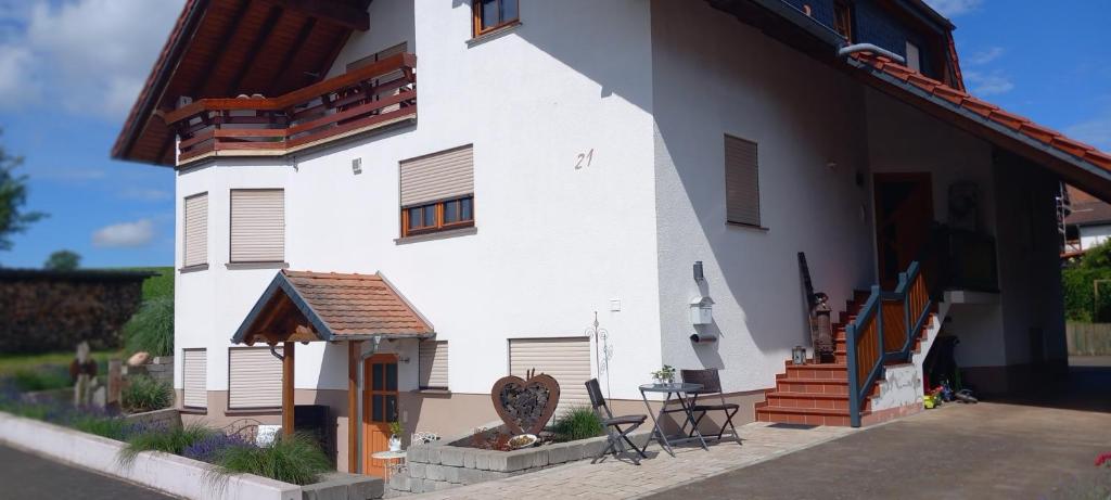 ein weißes Haus mit einem Tisch und Stühlen draußen in der Unterkunft Ferienwohnung Matheaperle in Nidda