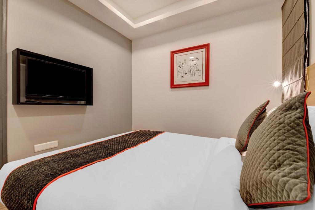 Super Townhouse Siri Residency في بانغالور: غرفة نوم مع سرير وتلفزيون بشاشة مسطحة