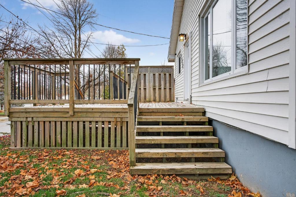 a house with a wooden staircase next to a fence at Abby's Place in Fredericton