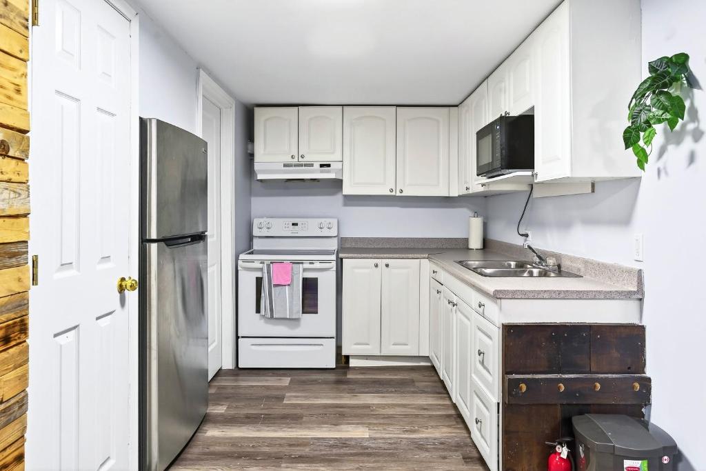 フレデリクトンにあるAbby's Lodgeの白いキャビネットとステンレス製の冷蔵庫を備えたキッチン