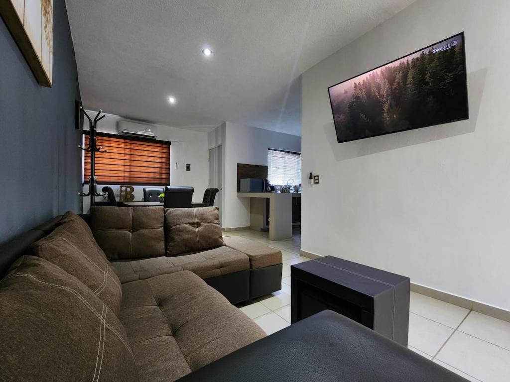a living room with a couch and a tv on the wall at Casa almendros 31 in Ciudad Guzmán