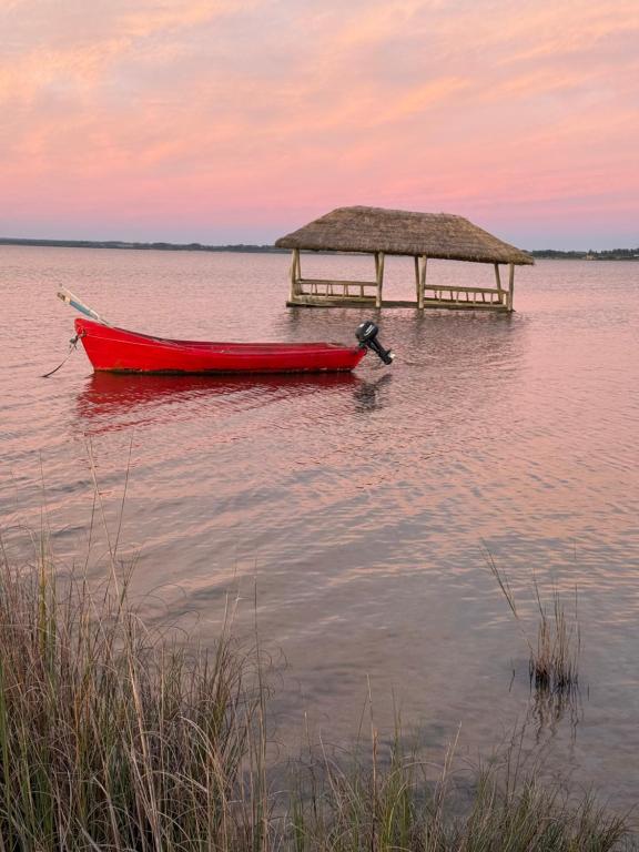 a red boat in the water next to a pier at Enigma in José Ignacio