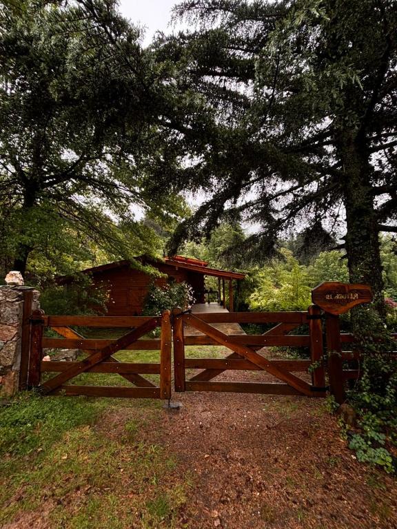 Cabaña Alpina con Terraza Panorámica في لا كومبريسيتا: حاجز خشبي مع بوابة امام شجرة