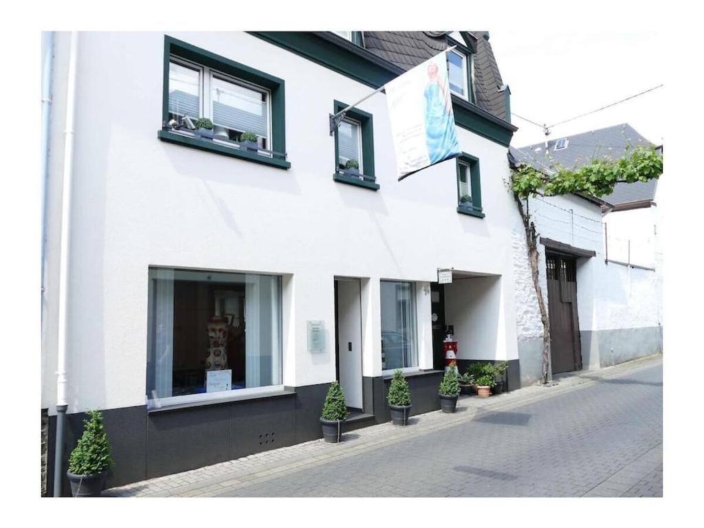 a white building with potted plants on a street at 4-star holiday apartments Weber in Winningen