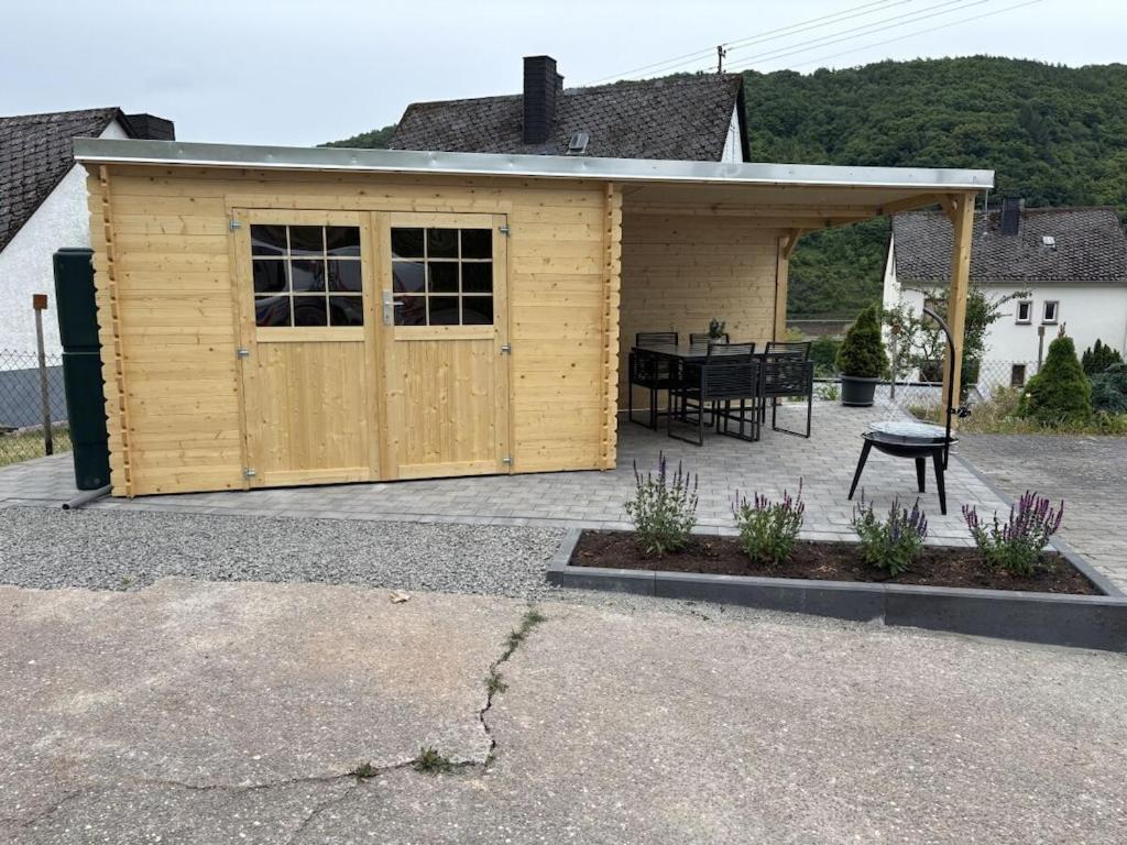 a wooden shed with a table and a patio at Holiday apartment Ina in Sankt Aldegund