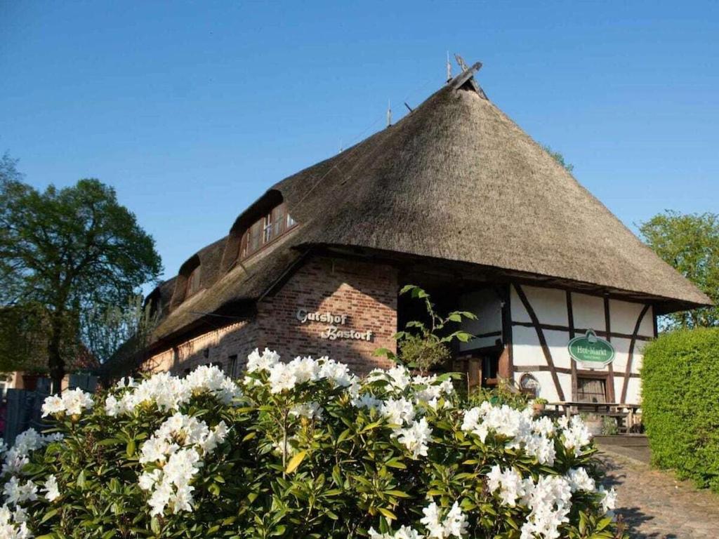 ein Gebäude mit Strohdach und Blumen davor in der Unterkunft Superior Studio in the Manor House in Bastorf