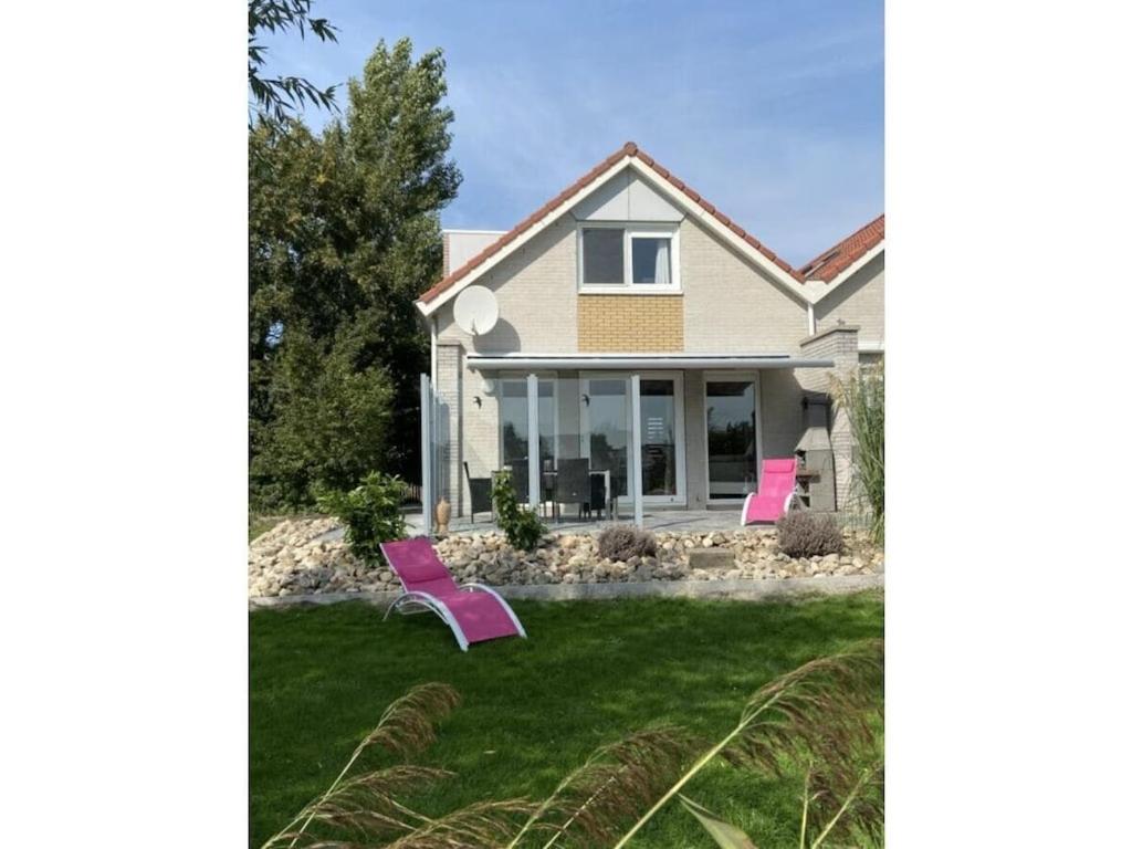 a house with pink chairs in the yard at Holiday home in Makkum with swimming pool in Holle Poarte