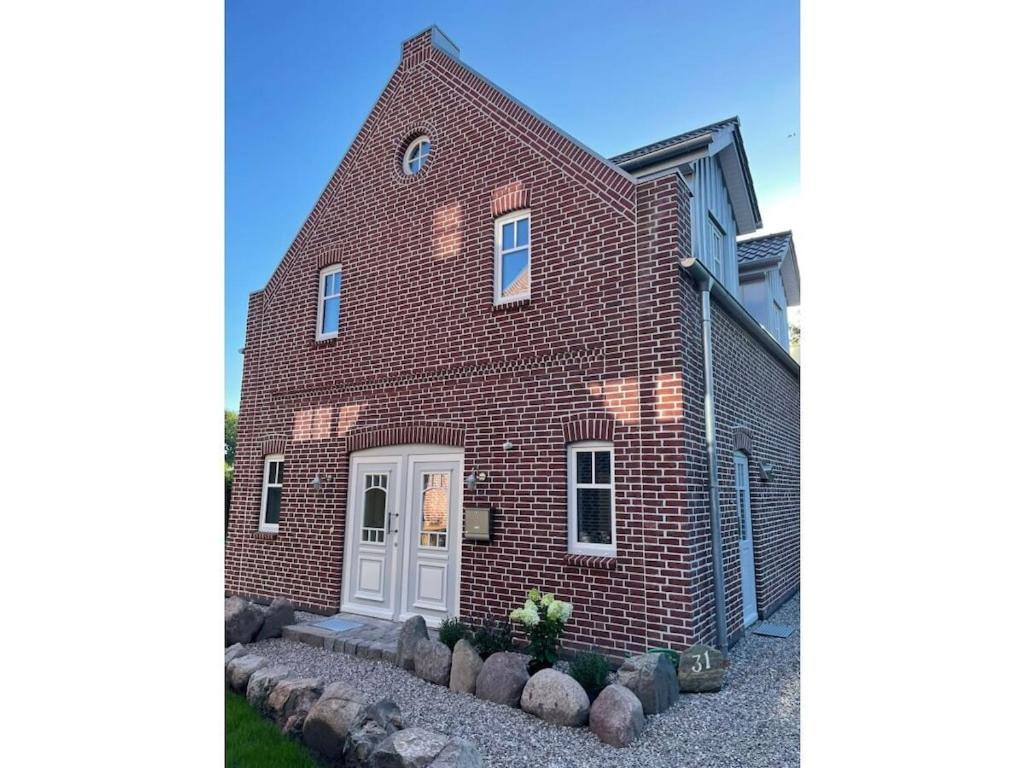 a brick house with a white door and some rocks at The Linnebargs, House 4 in Bisdorf