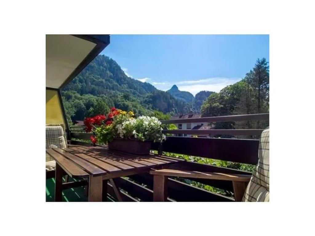 Holiday apartment with 1 bedroom في Kirchberg: طاولة خشبية مع ورود فوق الشرفة