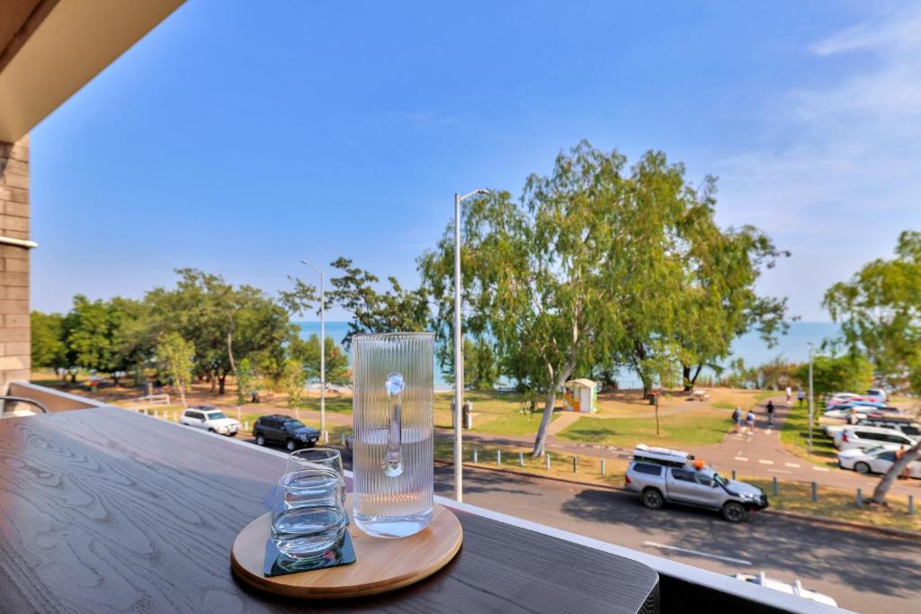due bicchieri su un vassoio di legno su un balcone con vista su un parcheggio di Ocean Vista Nightcliff Foreshore Apartment a Nightcliff