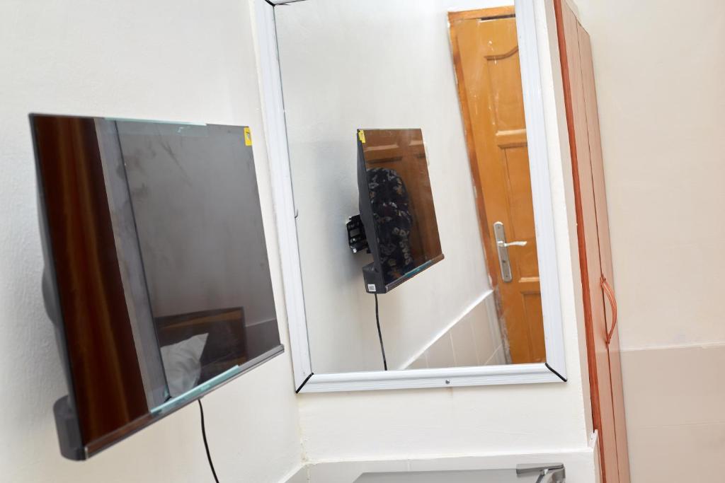 ein Spiegel an einer Wand neben einem Waschbecken in der Unterkunft Royal prima guest house, apartment and event center in Amanfro