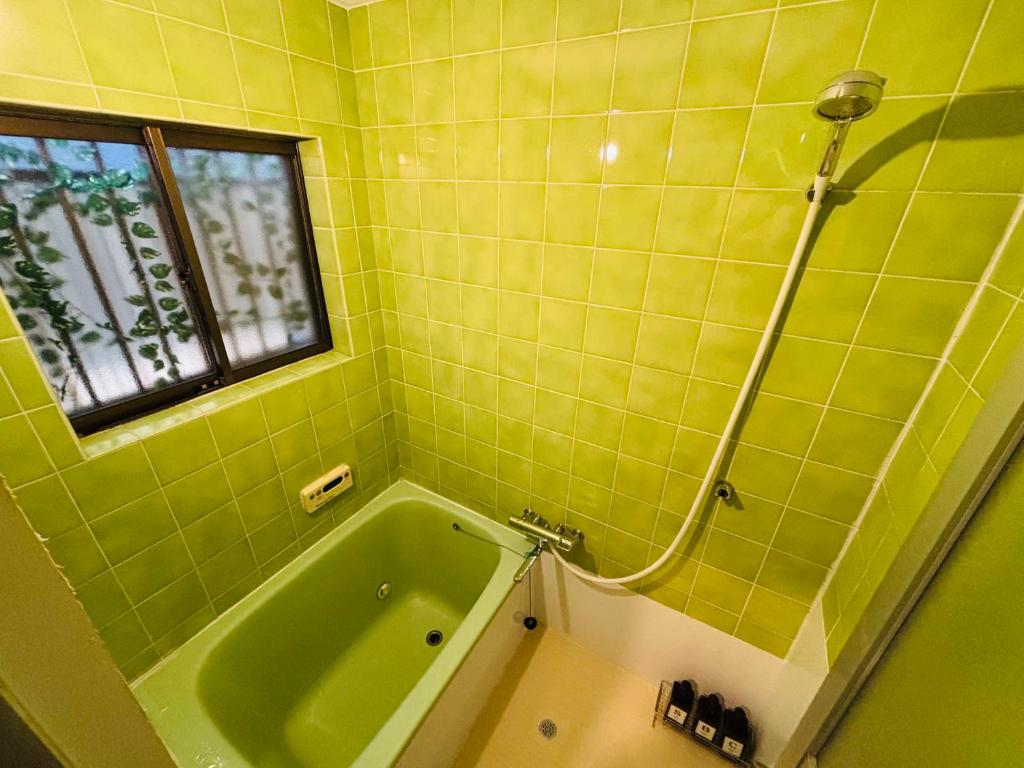 ein grünes Badezimmer mit Badewanne und Fenster in der Unterkunft いちえ堂 in Kashihara