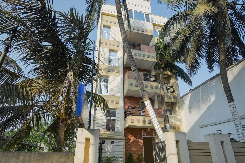 a tall building with palm trees in front of it at Hotel O Blue Sagar in Puri