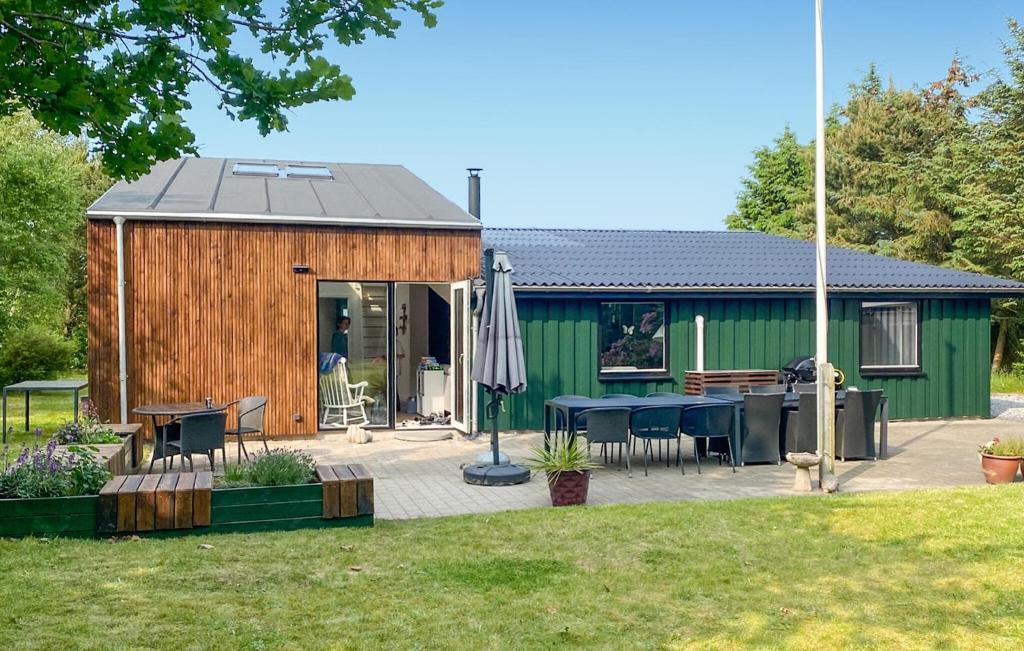 a green shed with a table and an umbrella at 4 Bedroom Awesome Home In Storvorde in Storvorde