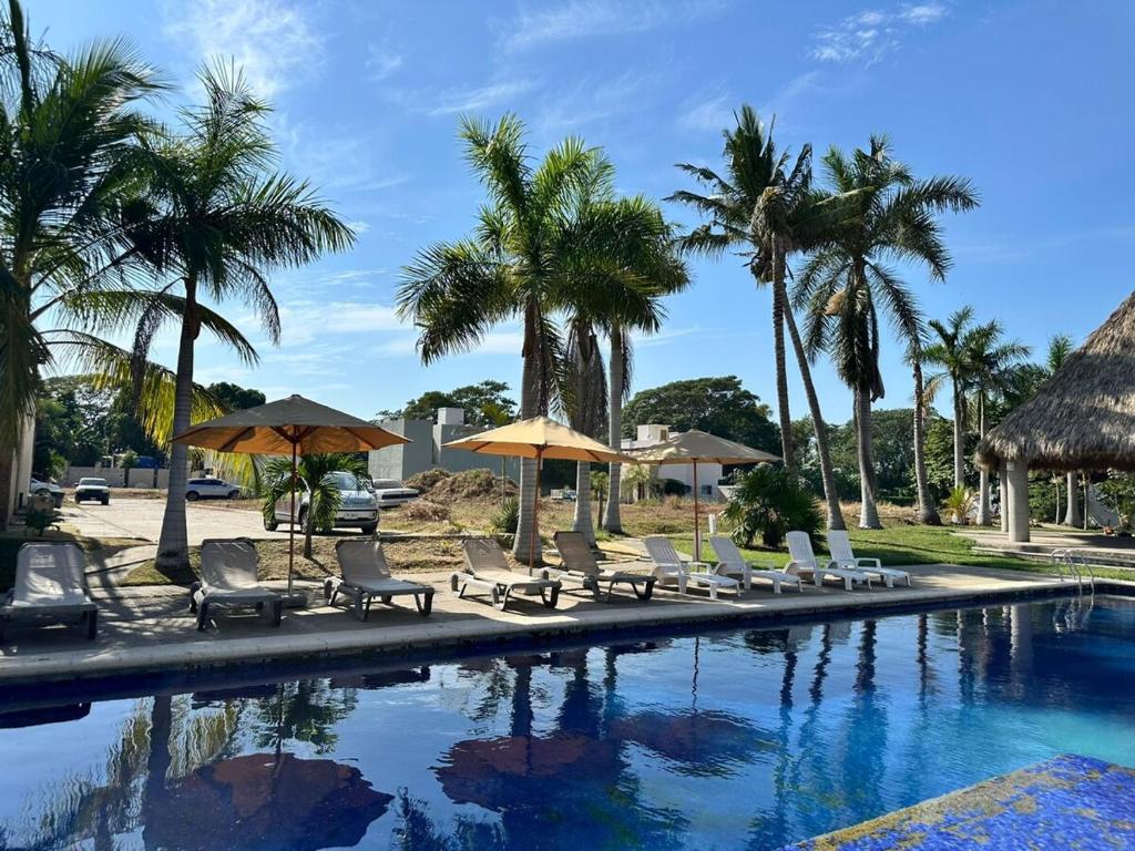 ein Pool mit Stühlen und Sonnenschirmen und Palmen in der Unterkunft La casa blanca in Mezcales