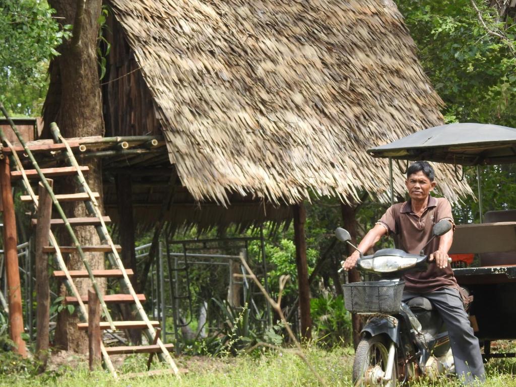 a man riding a motor bike with a basket at Siem Reap Tree Top Eco Lodge 
