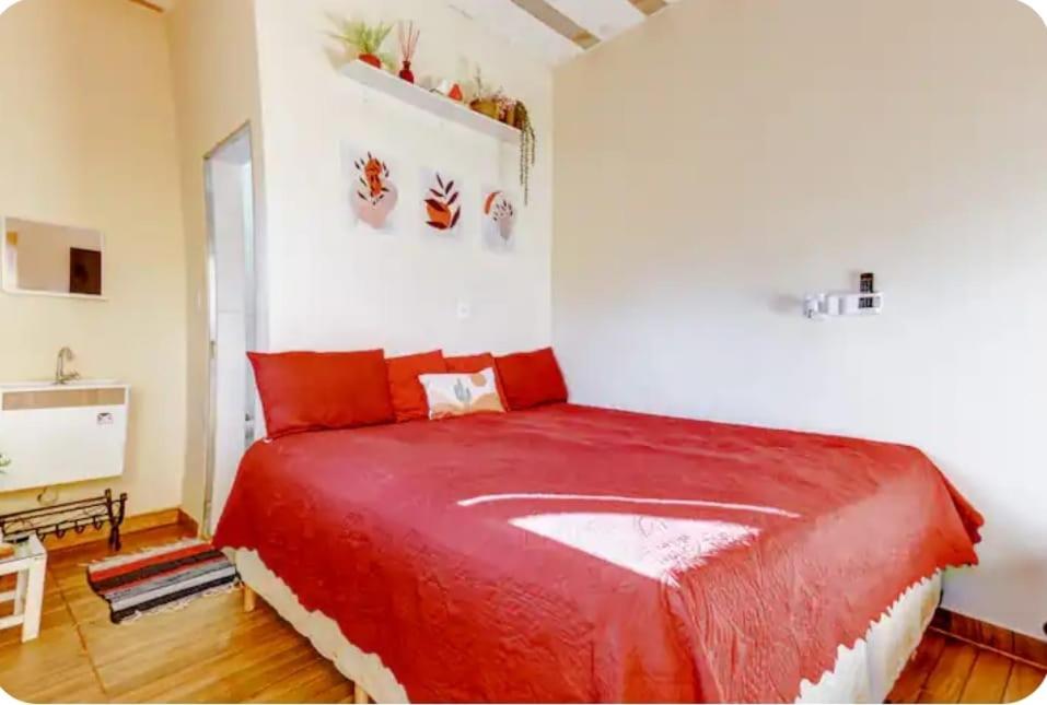 een slaapkamer met een groot rood bed in een kamer bij chale bella serra in Jaboticatubas