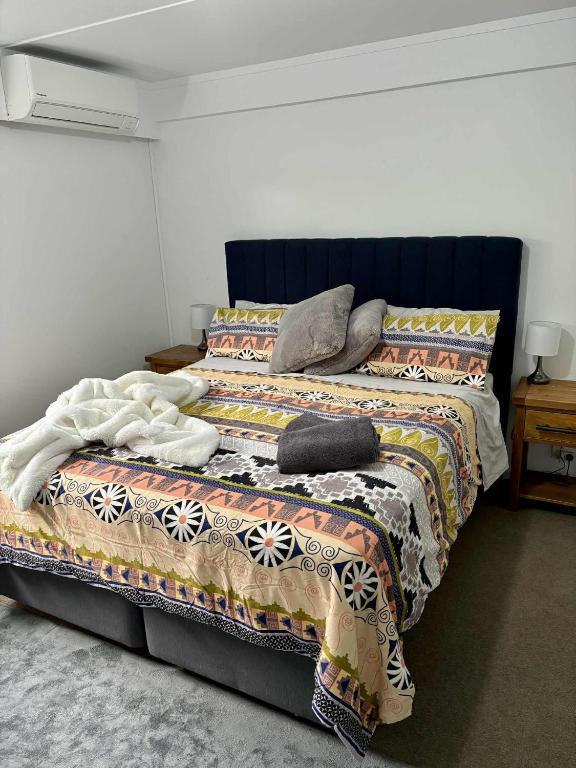 a bed with a blanket and pillows on it at Kiwi Cove in Tauranga