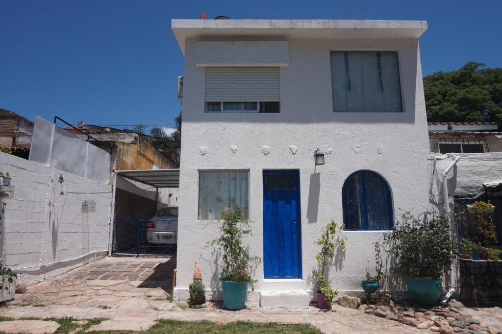 a white house with blue doors at Casita Meraki Duplex para 3 personas in Villa Carlos Paz