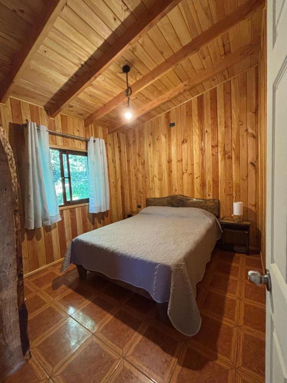 una camera da letto con un letto in una stanza di legno di Cabañas Troncos de Relin a Panguipulli