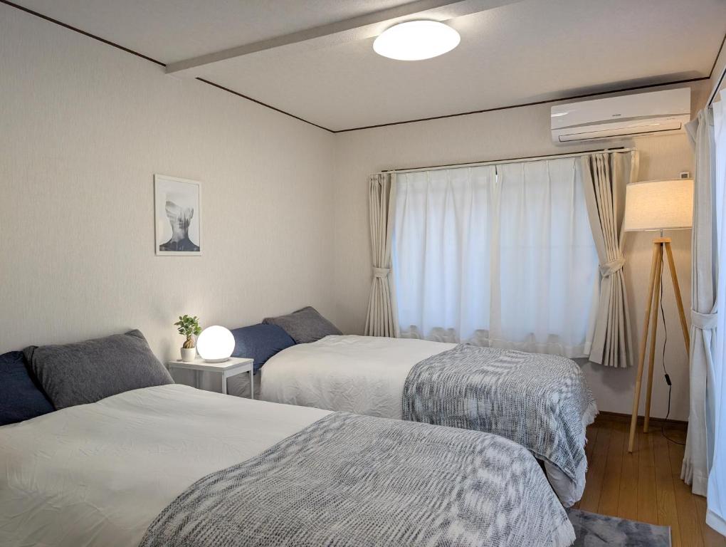 una camera da letto con due letti e una finestra di ann近島 無料駐車場2台 階段なし安心の平屋貸切 ファミリーやグループ旅行に最適 a Gifu
