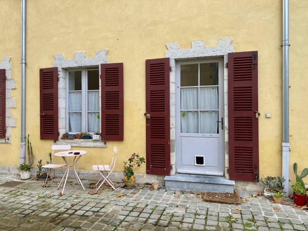 a yellow building with two windows and a table and chairs at Charmant T2 Larressore - Parking Privé - WiFi Inclus - FR-1-495-156 in Larressore